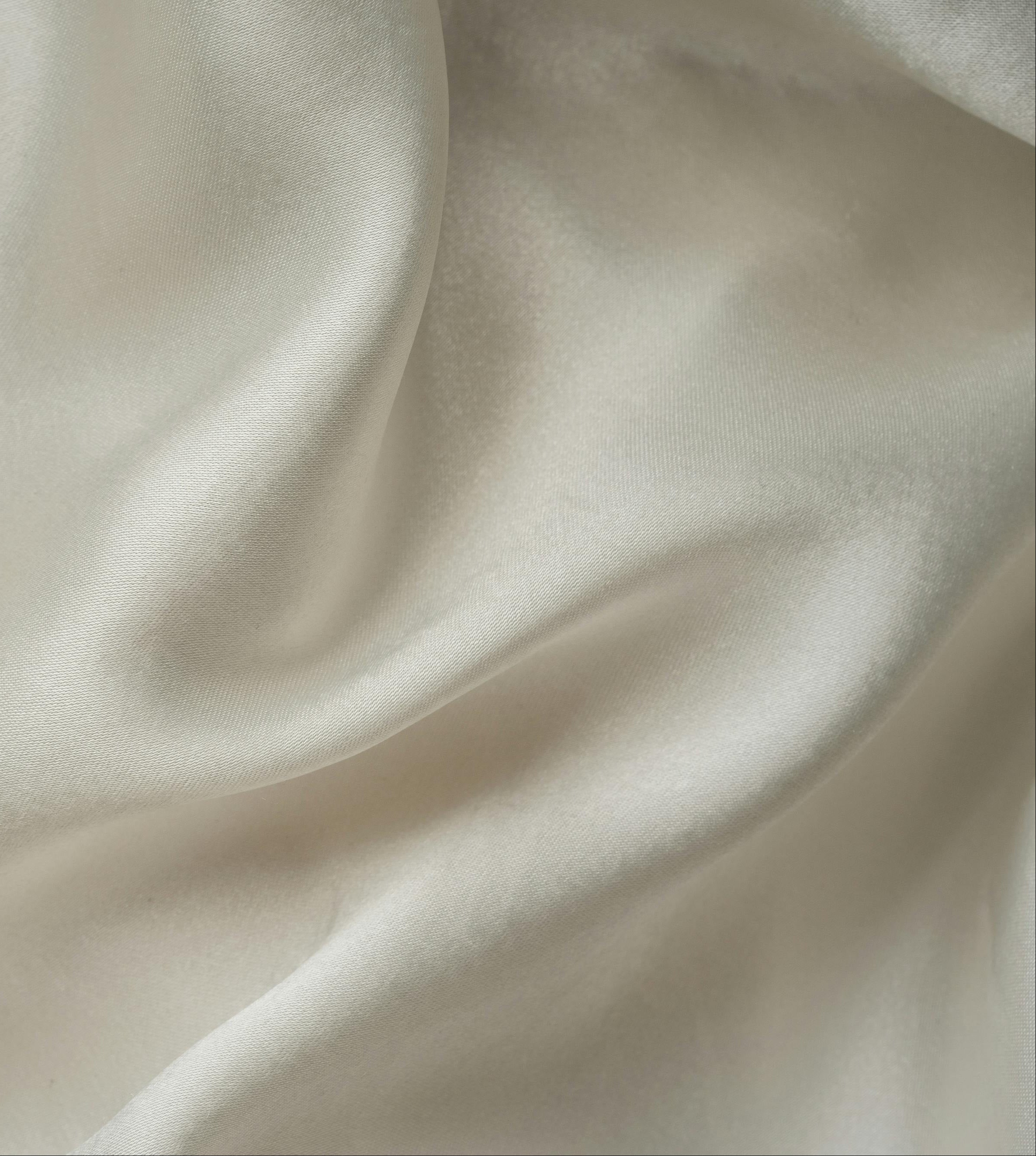 Close-up of beige satin fabric with soft folds